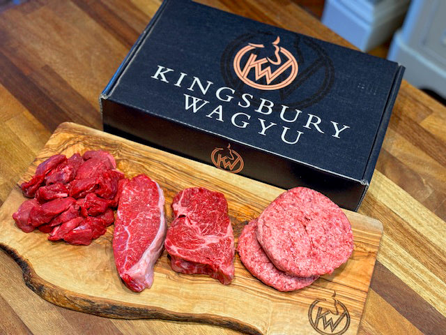 Kingsbury Wagyu Beef Variety pack showing contents; 500g steak pieces, sirloin steak, ribeye steak and 2 wagyu burgers on a chopping board alongside the gift box it presents in